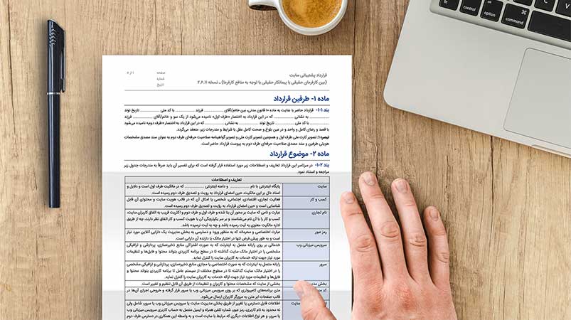 نمونه قرارداد پشتیبانی سایت در حال امضا در کنار لپ تاپ